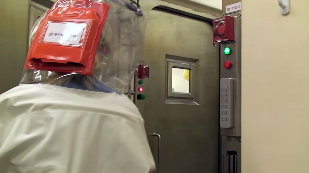 A scientist in a positive-pressure suit opens an air pressure resistant door into a maximum containment biosafety lab