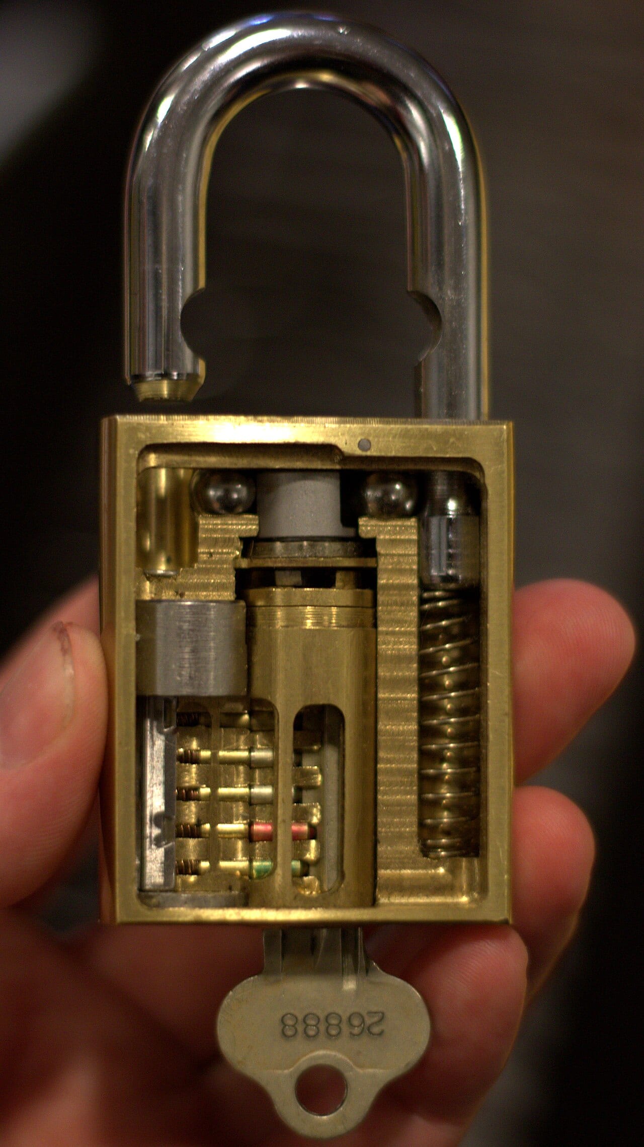 A cutaway padlock shown open, its locking pins exposed