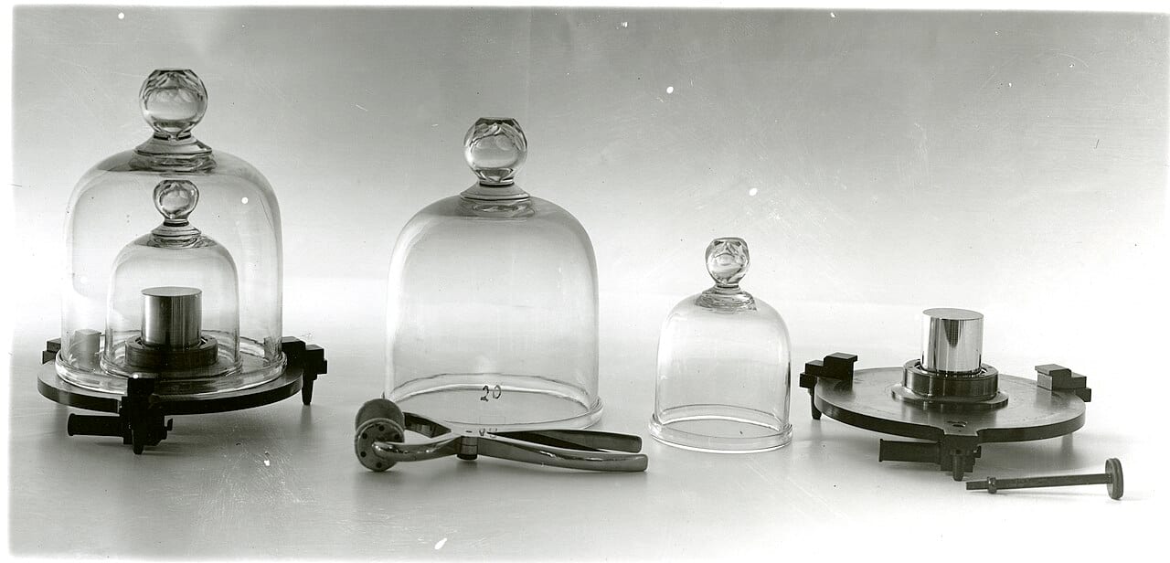 A platinum-iridium cylinder, once the United States' primary kilogram standard, next to newer calibration equipment