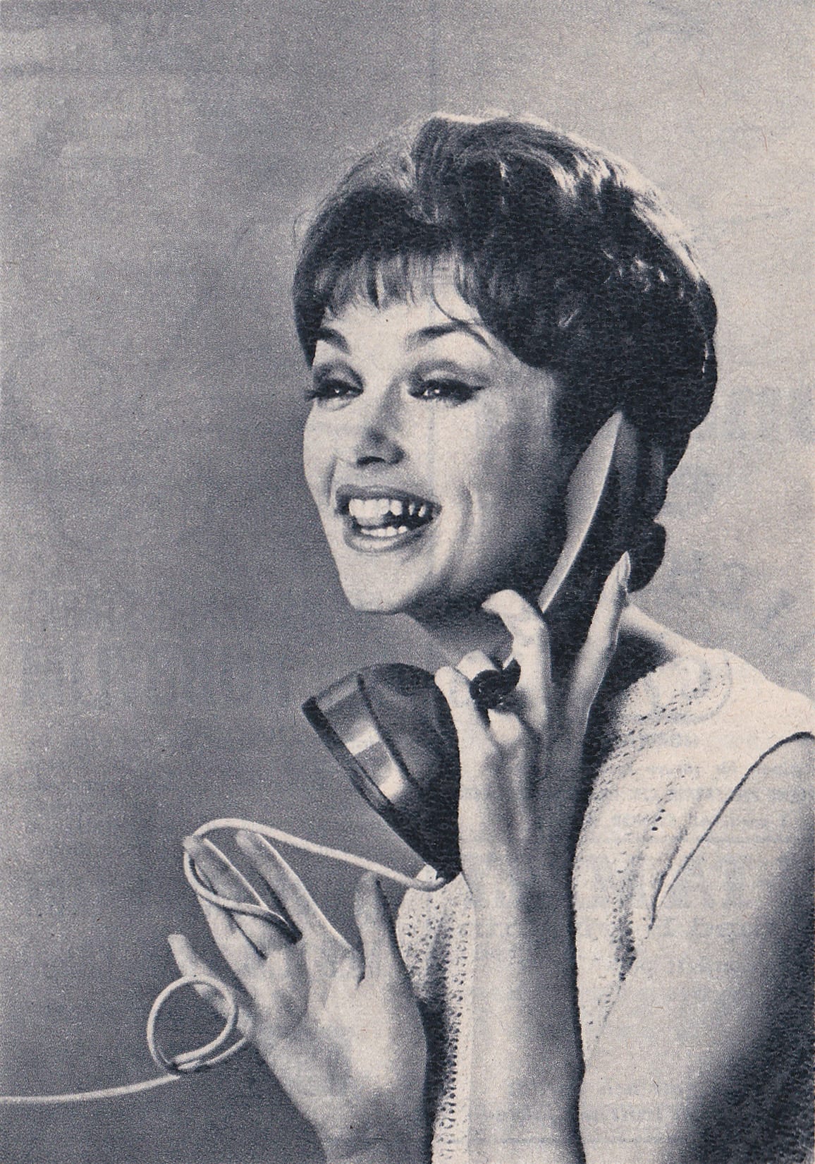 A woman speaks into a telephone receiver in 1961