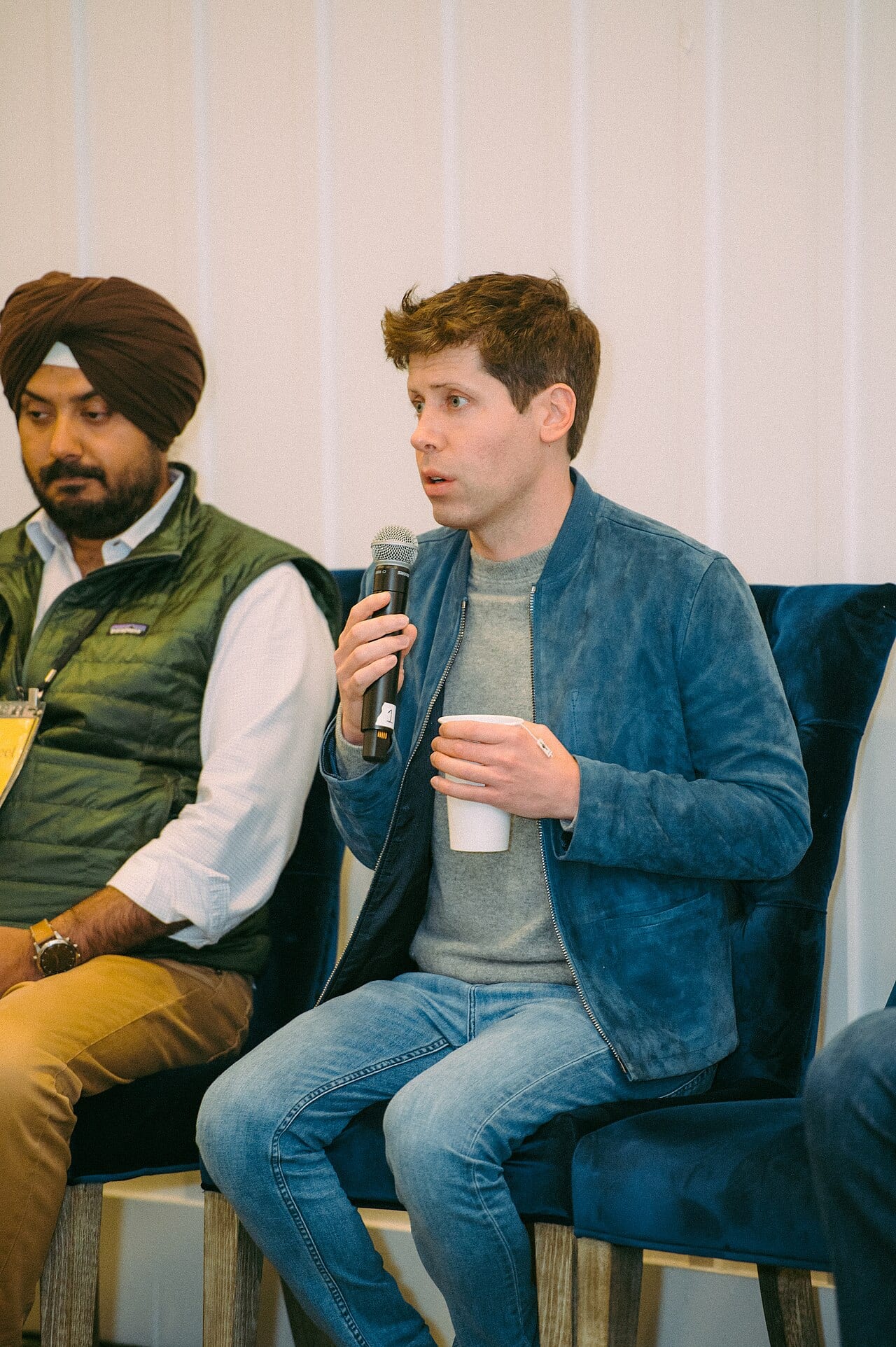Sam Altman speaks on stage holding a microphone