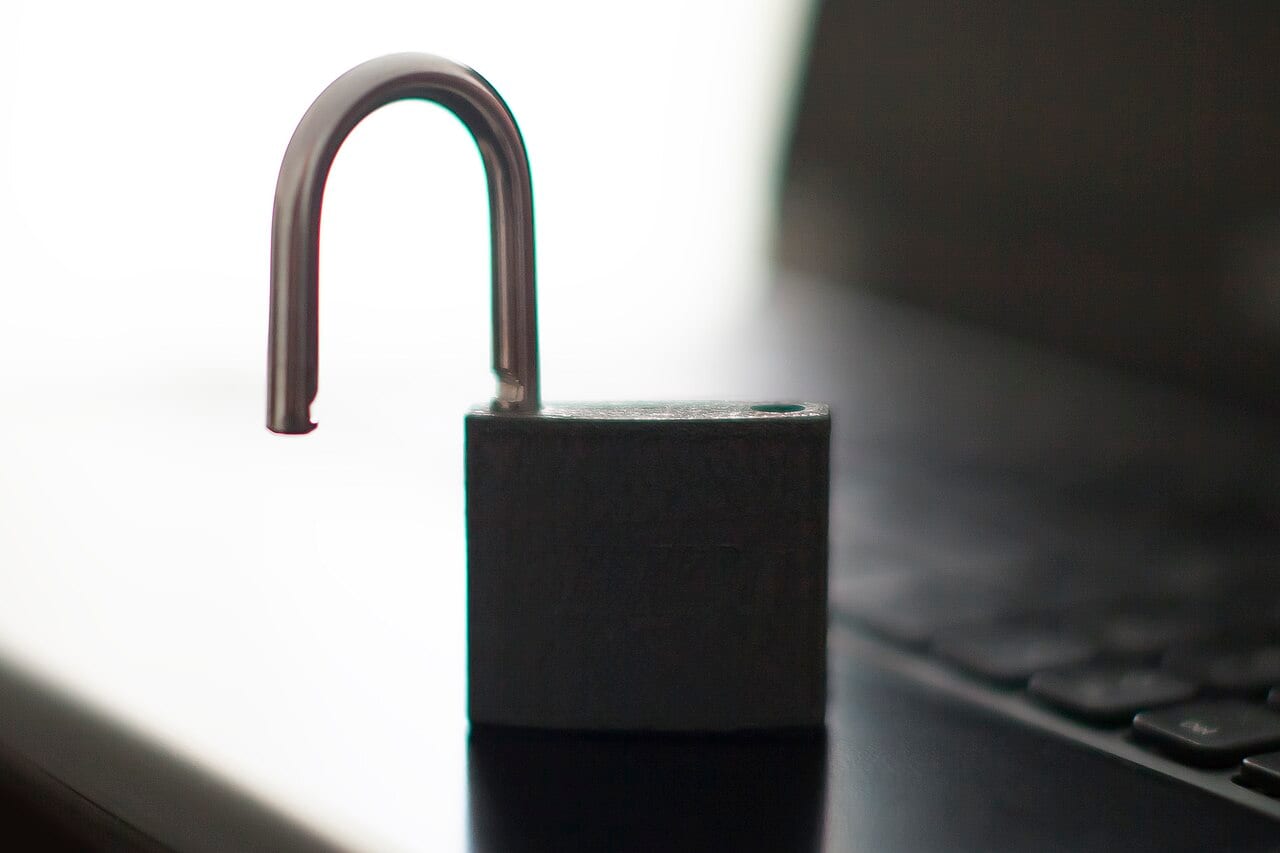 An open padlock resting on a laptop keyboard