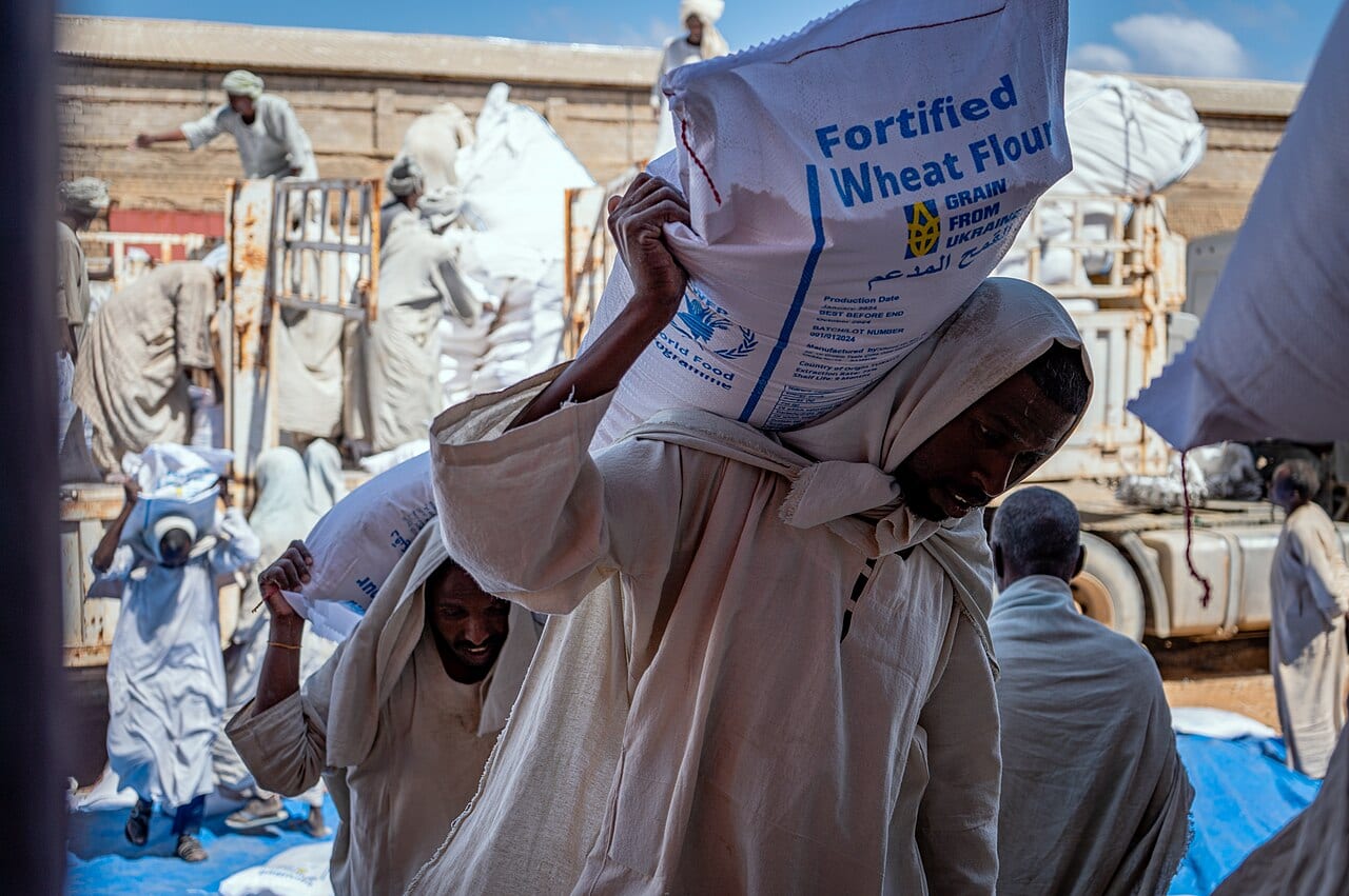 Porters carry World Food Programme sacks of fortified wheat flour from trucks to a warehouse in Port Sudan
