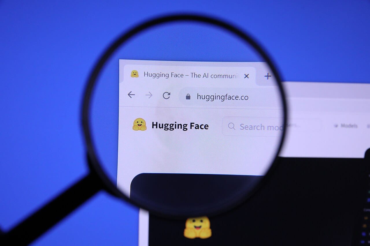 A magnifying glass held over the Hugging Face website homepage