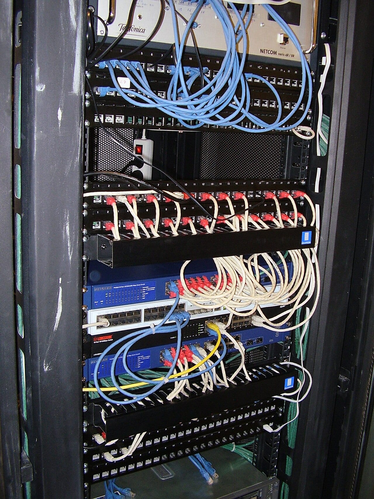 A telecommunications rack shows network cabling and patch panels