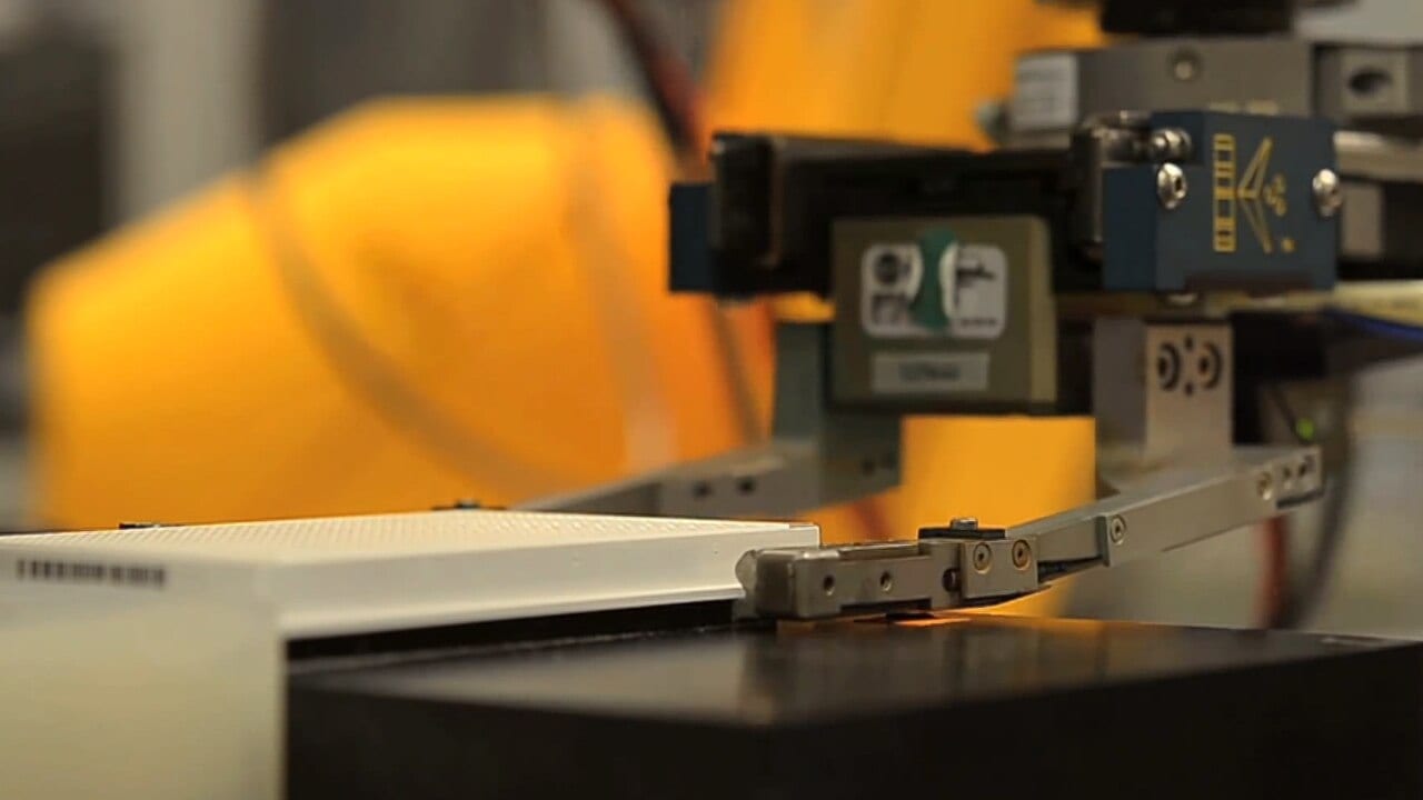 A robot arm handles a lab plate during an automated testing run